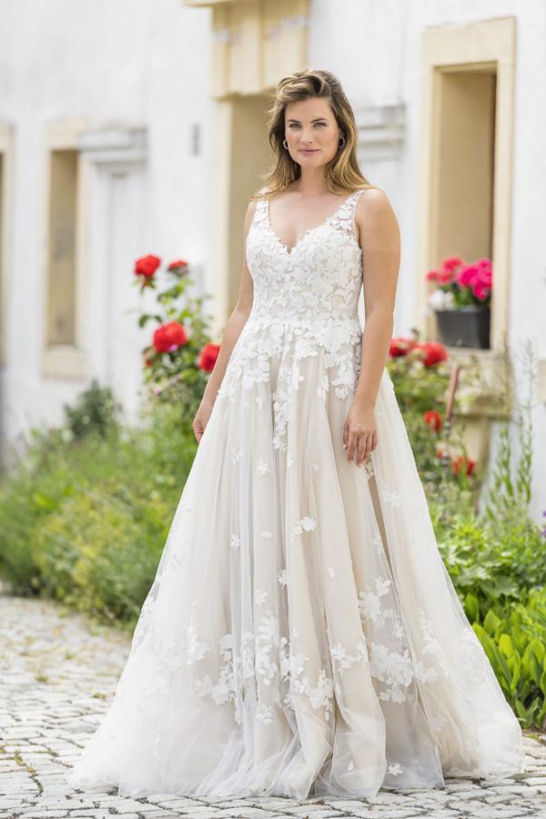 Foto einer Braut in weißem Kleid vor schöner Kulisse im Sommer 